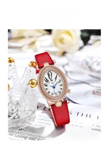 Détail de la montre ovale en or rose avec bracelet en cuir rouge et lunette en strass
