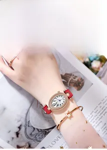 Détail de la montre ovale en diamants avec bracelet cuir rouge et bracelet étoile en or