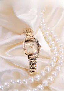 Detail view of rose gold square watch with faceted glass dial on silk with pearls
