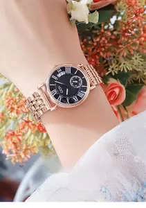 Close-up of women's rose gold mesh strap watch with black dial and calendar display