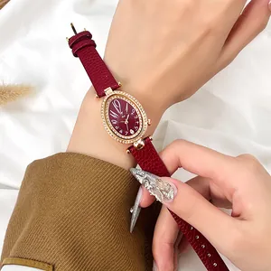 Montre dorée ovale pour femme avec lunette en diamant et bracelet en cuir rouge
