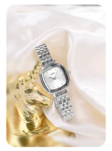 Macro shot of a square silver quartz watch with steel mesh band on white silk fabric