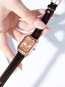 Detail der roségoldenen rechteckigen Uhr mit Datumsanzeige und braunem Lederband