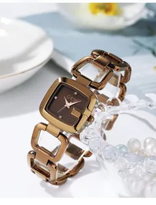 Gros plan d'une montre élégante en or rose avec cadran carré et bracelet à maillons évidés
