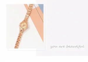 Detailed close-up of rose gold watch dial with quartz movement and crystal hour markers