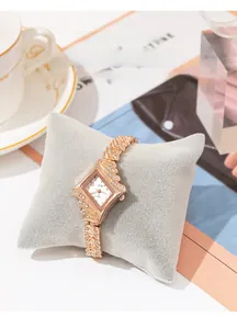 Macro view of rose gold rhombus watch with rhinestones on a grey velvet pillow
