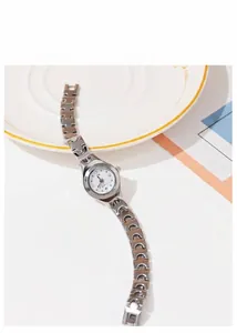 Detail of a chic silver quartz watch with a white rhinestone dial on a white ceramic plate