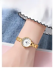 Close-up of a women's gold quartz watch with a small white dial on a wrist