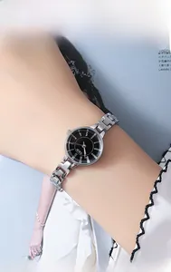 Close-up of a stylish silver metal watch with a black dial worn on a female wrist