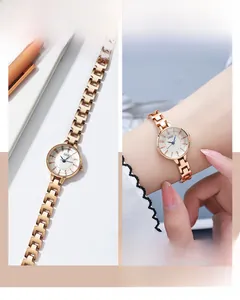 Detail of rose gold metal link strap and small round dial on women's quartz watch