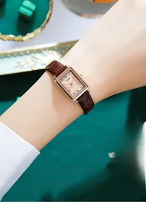 Nahaufnahme einer runden Gold-Armbanduhr mit braunem Lederarmband am Handgelenk