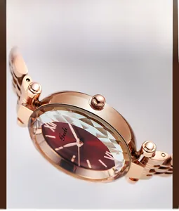 Gros plan d'une montre en or rose avec verre taillé en diamant et cadran rouge foncé