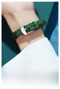 Detail of dark green crocodile texture leather watch strap with silver metal pin buckle