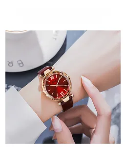 Close-up of elegant women's watch with red sunray dial and gold textured bezel
