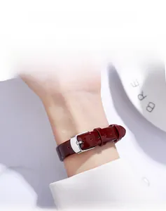 Close-up of flexible red patent leather watch strap with a silver metal pin buckle
