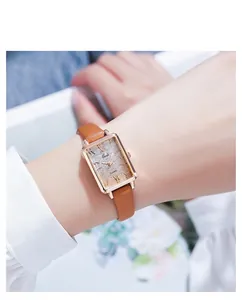 Elegant rectangular rose gold watch with brown leather strap on model's wrist