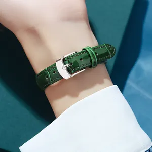 Deep green crocodile leather watch strap with silver buckle on elegant white shirt cuff