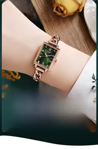 Close-up of elegant rose gold chain watch with emerald green square dial on a model