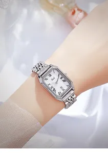 Gros plan d'une montre carrée argentée avec chiffres romains au poignet féminin