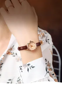 Photo de style d'une montre ronde dorée avec bracelet en cuir marron au poignet