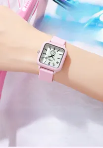 Detailed view of pink square quartz watch with silicone strap on wrist with soft lighting