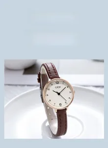 Close-up of minimalist rose gold quartz watch with round dial and brown leather strap