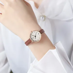 GEDI minimalist women's watch with round rose gold case and brown leather strap on wrist