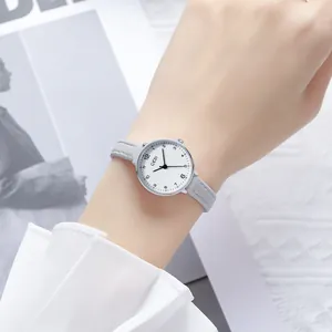 Minimalist quartz watch with silver round case and grey leather strap on woman wrist