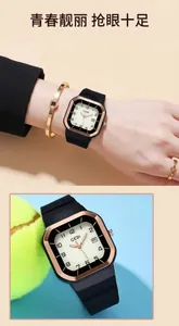 Détail du boîtier carré en or rose avec aiguilles lumineuses et guichet de date sur bracelet silicone