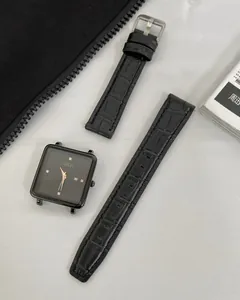 Detail of square quartz watch with black dial, gold markers and leather strap