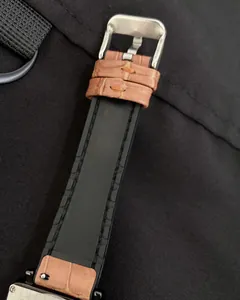 Detail of square watch strap featuring black silicone with brown leather accents and buckle