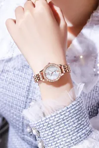 Detail of rose gold ladies watch featuring a crystal bezel and pearl dial on wrist