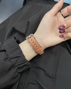 Close-up of brown crocodile embossed texture watch strap with silver buckle on wrist