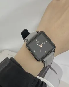 Detail of square quartz watch with black dial, rose gold markers and grey leather strap