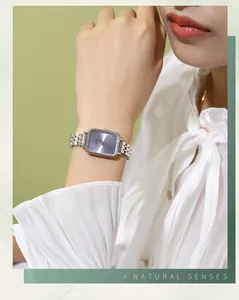 Close-up of a silver stainless steel square watch with a sunray blue dial on a wrist