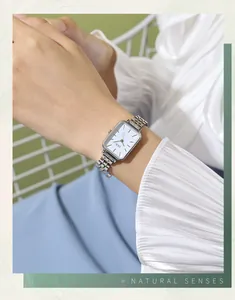 Silver rectangle metal watch with white dial shown on wrist with elegant white blouse