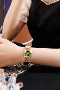 Close-up of vintage square gold watch with green sunray dial on a female wrist