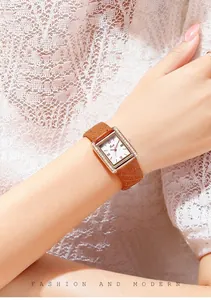 Close-up of a rectangular rose gold watch with quilted brown leather strap on wrist