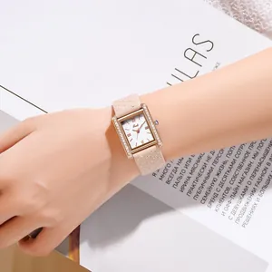 Close-up of a women's gold rectangular quartz watch with quilted leather strap on a wrist