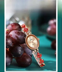 Detail einer roségoldenen Quarzuhr mit rotem Edelsteinarmband auf kreativem Display