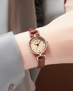 Detailed side view of a rose gold quartz watch with a brown leather strap on a wrist