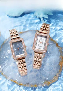 Dettaglio di due orologi quadrati in oro rosa su uno sfondo di agata e riflessi d'acqua