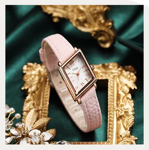 Close-up of a vintage rose gold watch with a pink leather strap on green silk