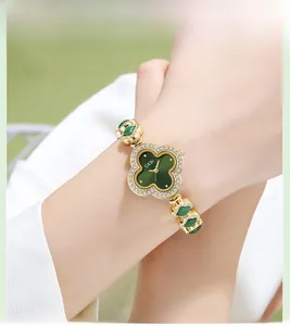 Close-up of gold-plated women's watch with green clover motifs and crystal bezel