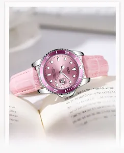 Detail of luxury women's watch with pink dial, purple bezel, and leather strap on a book