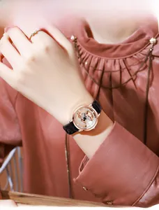 Close-up of rose gold watch with crystal bezel and black leather strap on a model wrist