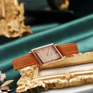 Vintage rose gold square quartz watch with brown leather strap on green silk