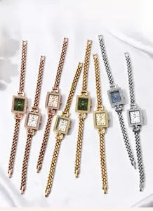 Detailed flat lay of Gedi square dial quartz watches with diamond bezels on white silk