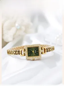 Detail of square quartz watch with emerald green sunburst dial and rhinestone bezel