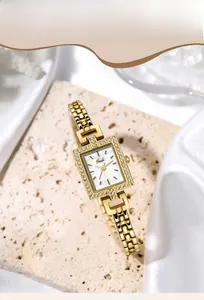 Close-up of gold alloy bracelet watch with square rhinestone bezel on stone surface